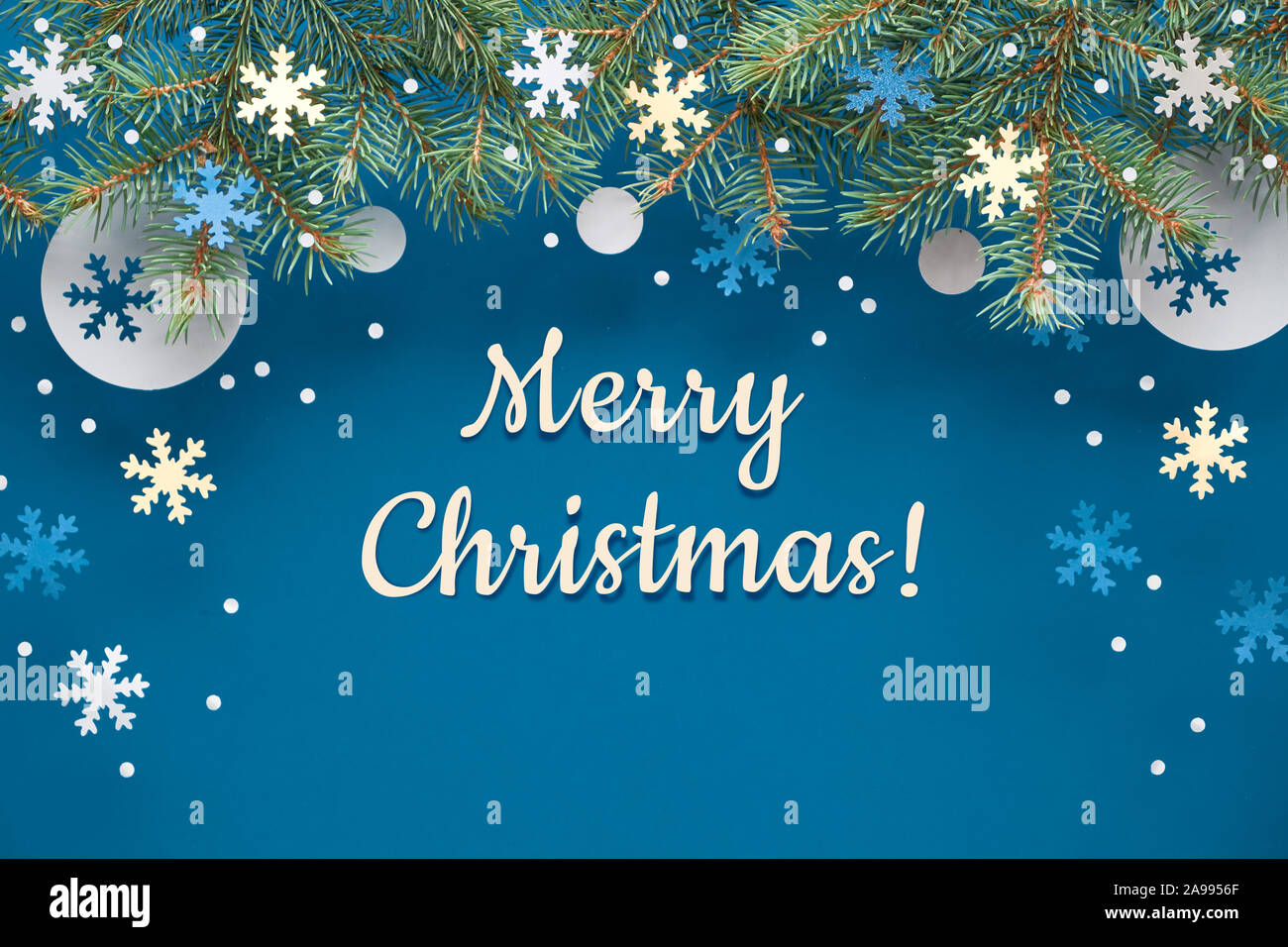 Festive Christmasr sfondo con ramoscelli di abete e blue white paper decorazioni. Appartamento laico, vista dall'alto sulla luce blu sullo sfondo della carta con carta di saluto t Foto Stock
