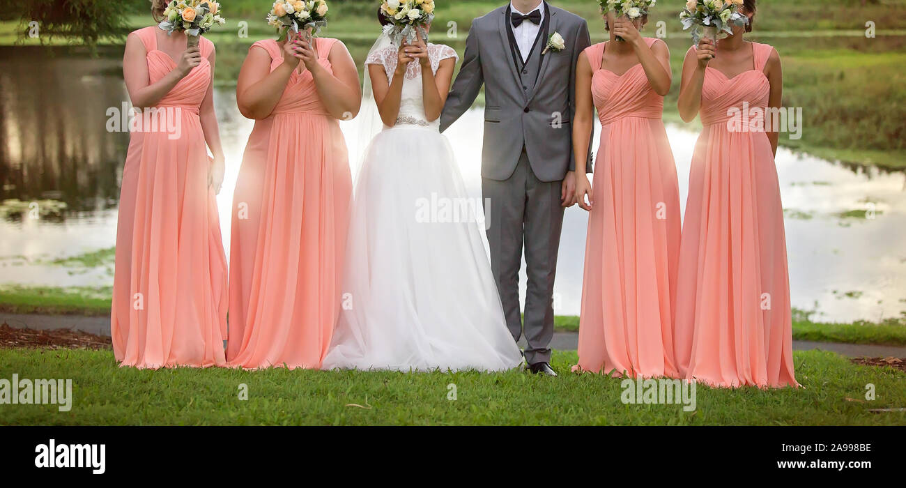 Sposa e le sue damigelle hanno lo sposo in posa divertente con mazzi dopo la cerimonia di nozze Foto Stock
