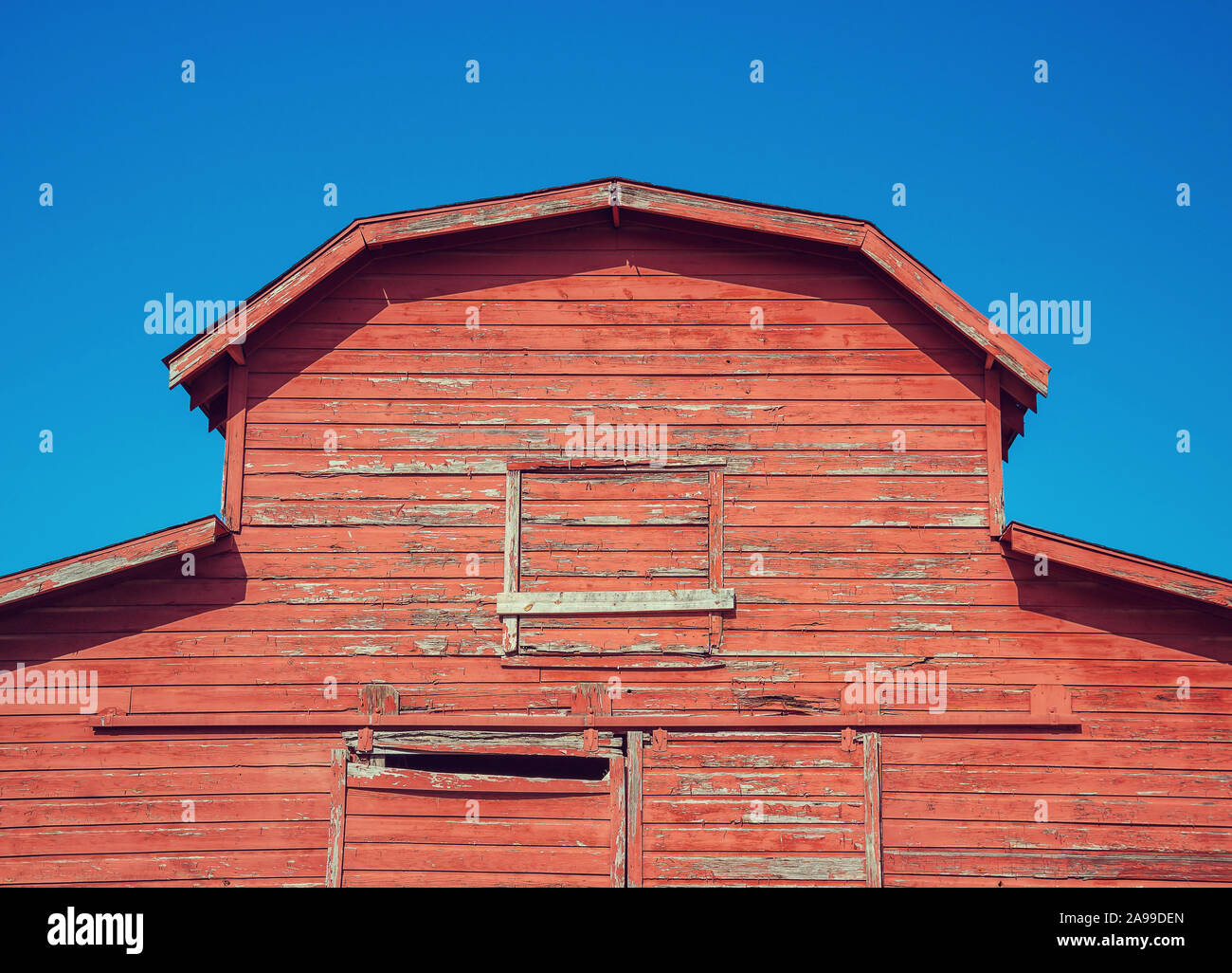 In alto di un vecchio e rustico e stagionato granaio rosso. Blu brillante sullo sfondo del cielo. Foto Stock