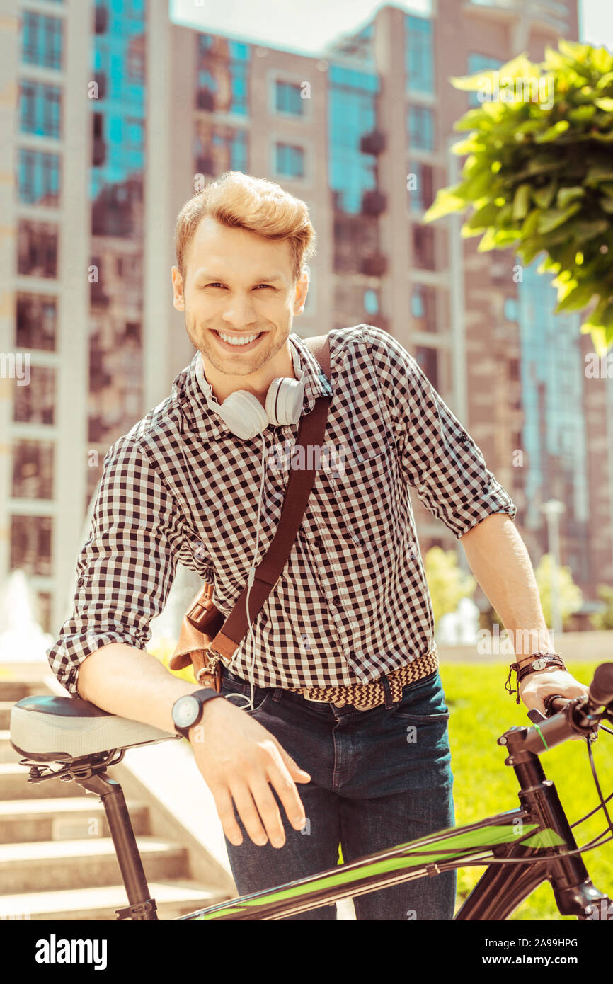 Allegro biondo uomo appoggiato sulla sua bicicletta Foto Stock