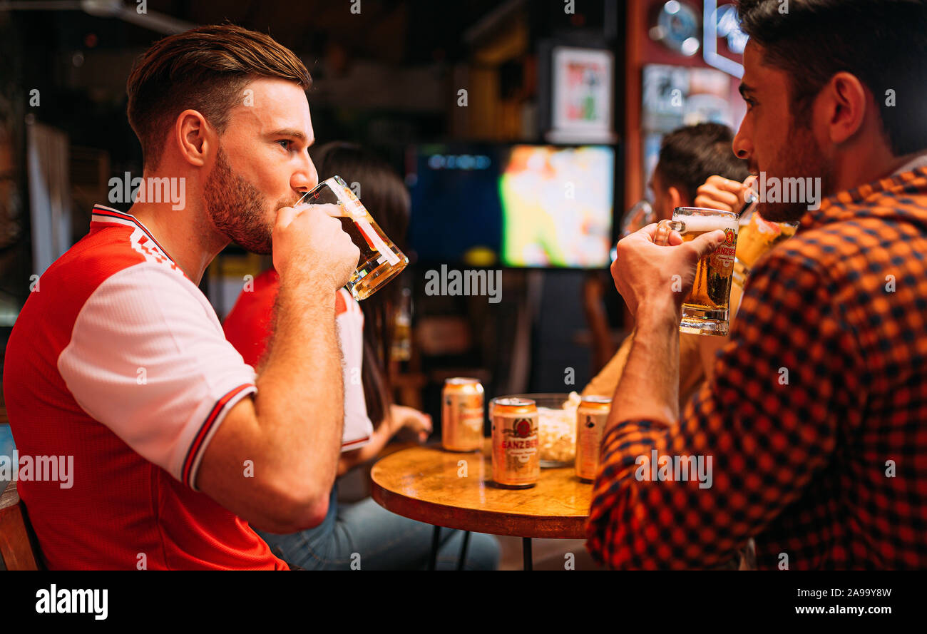 Party entusiasta gli appassionati di arsenale che guardano il calcio con Ganzberg Beer in il pub Foto Stock