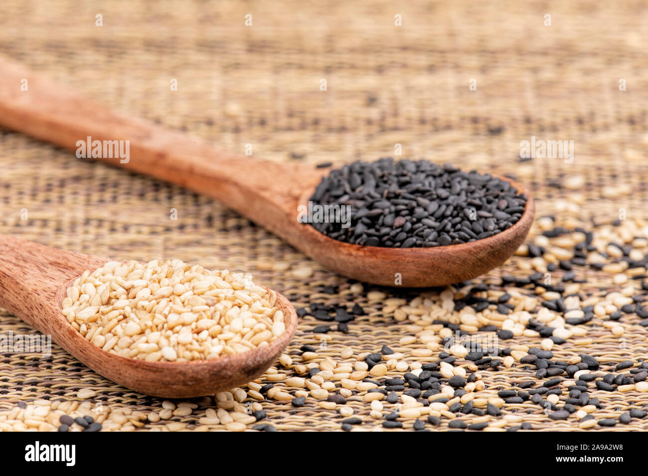 Cucchiai di legno pieno di sana e deliziosa di semi di sesamo e di semi di sesamo nero su uno sfondo a trama Foto Stock