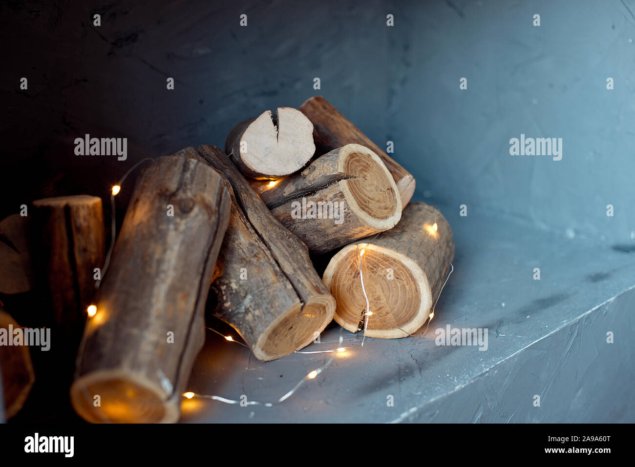 I log di un albero sono collocati sulla parete. Imitazione di un caminetto nella parete, le luci di una ghirlanda di fiori con i registri Foto Stock