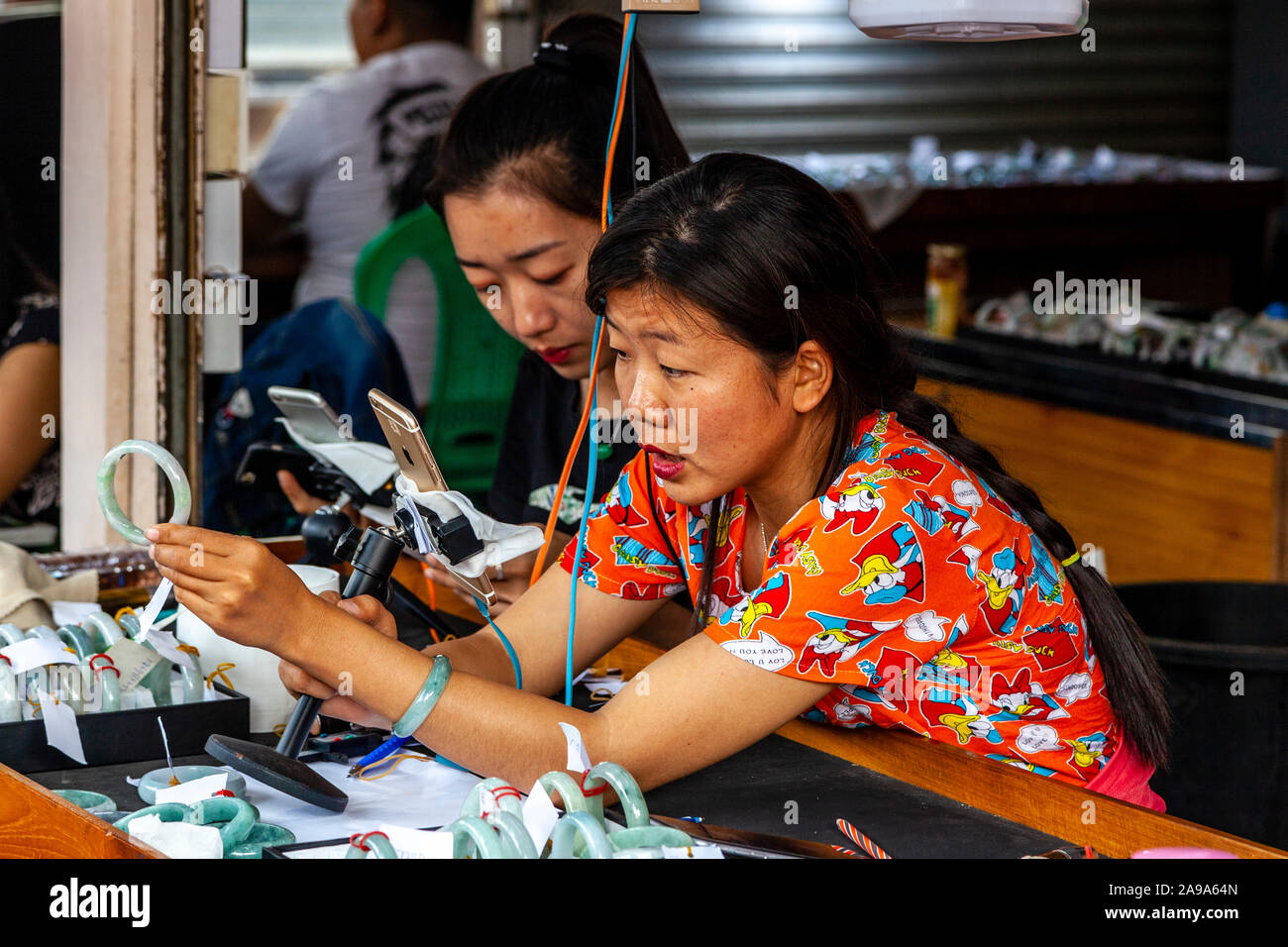 Una femmina di concessionari esaminando Jade al Mercato della Giada, Mandalay Myanmar. Foto Stock