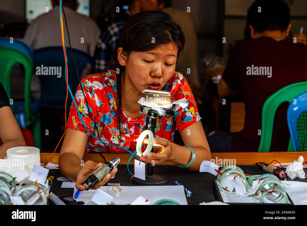 Un concessionario femmina esaminando Jade al Mercato della Giada, Mandalay Myanmar. Foto Stock