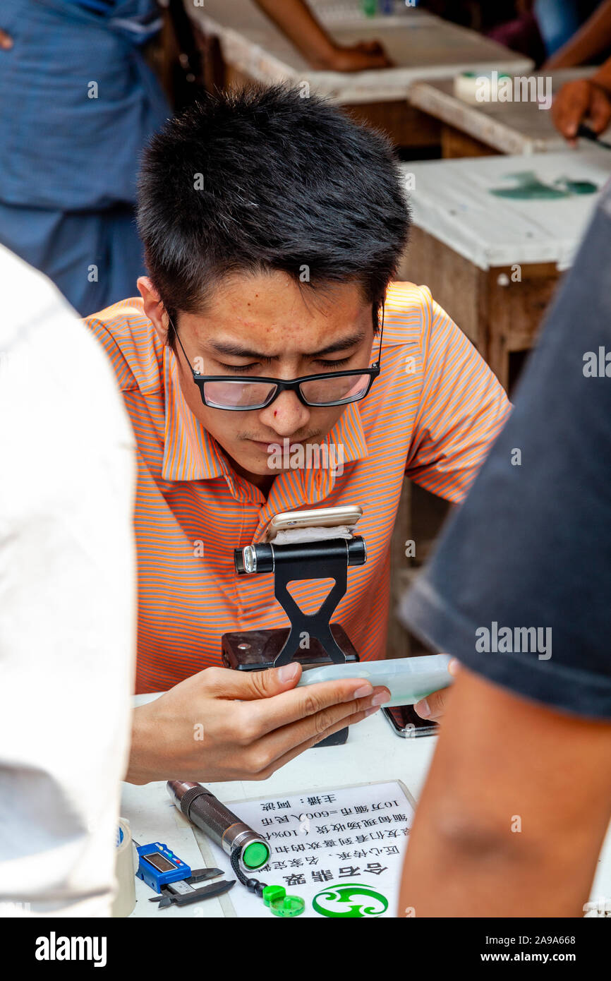 I concessionari esaminando Jade al Mercato della Giada, Mandalay Myanmar. Foto Stock