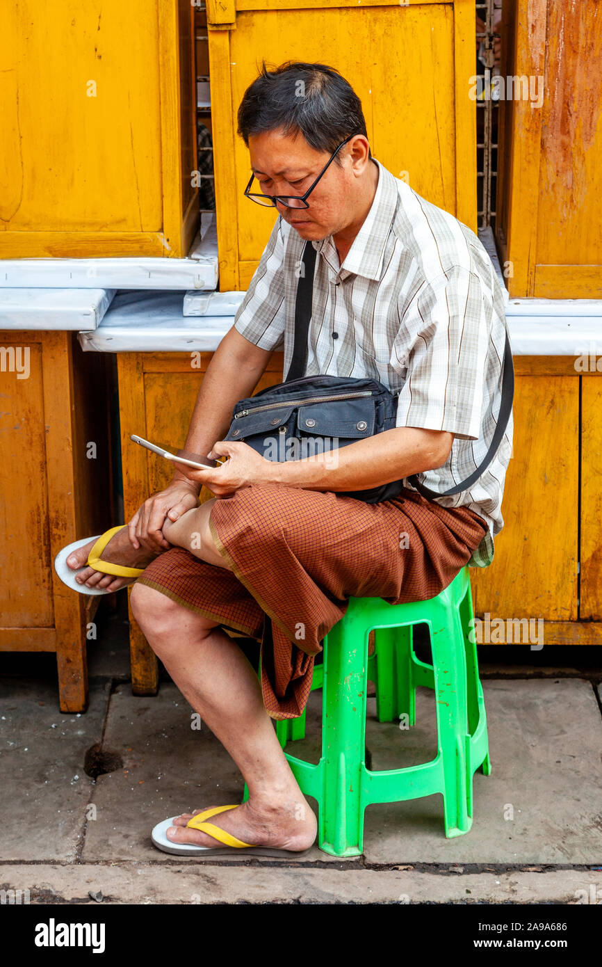 Un uomo locale utilizzando un telefono cellulare al Mercato della Giada, Mandalay Myanmar Foto Stock