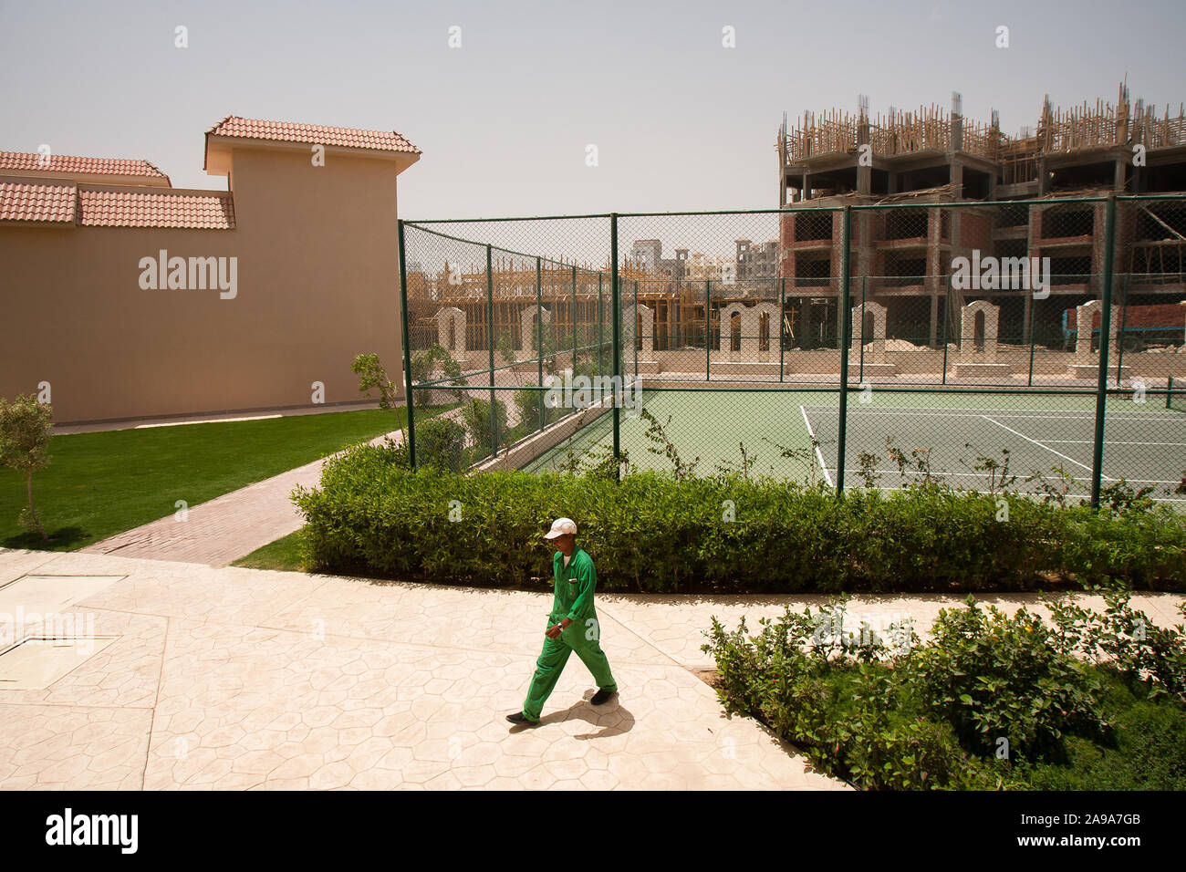 Hurghada, Egitto, 27 Aprile 2008: un lavoratore passa in un hotel con campi da tennis vicino a un grande sito di costruzione di un nuovo hotel. Foto Stock