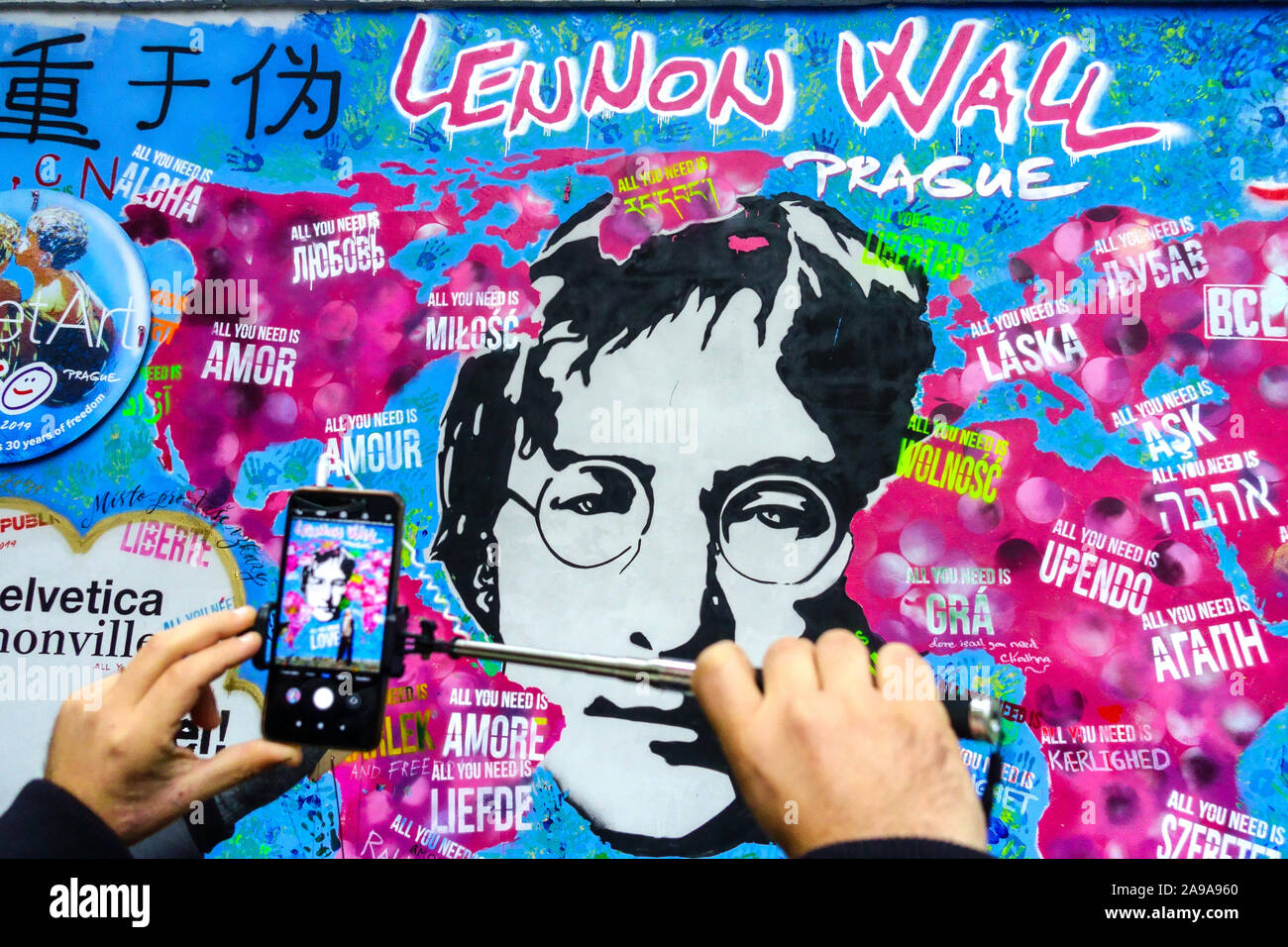 Uomo che scatta una foto su cellulare al John Lennon Wall Prague Street art graffiti Foto Stock