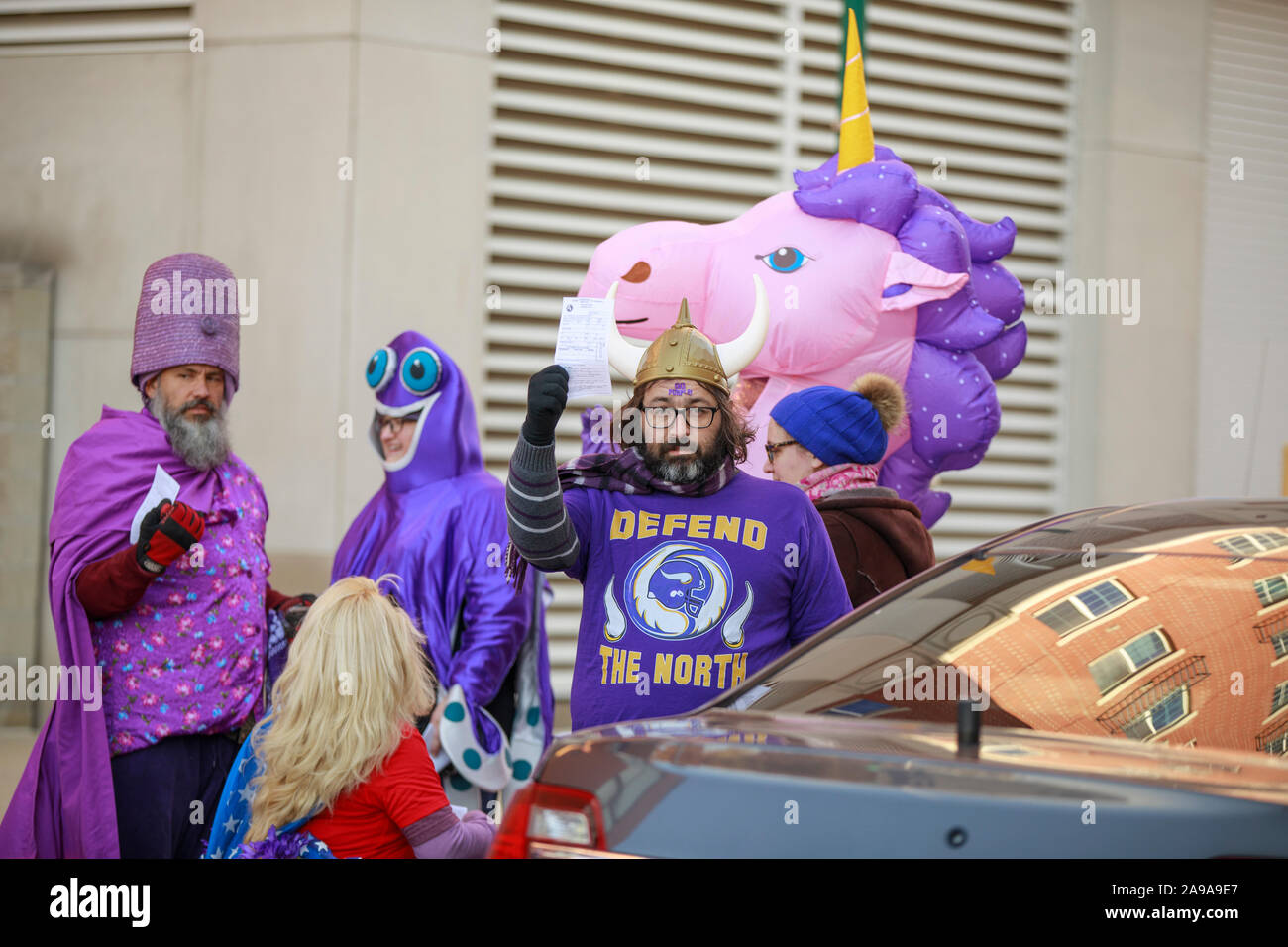 Bloomington, Stati Uniti. 09Nov, 2019. Un membro della maglietta viola brigata fa un gesto durante la protesta.La polizia ha arrestato gli attivisti vestito come un gigante unicorn, Wonder Woman e i Vichinghi dopo che essi hanno dimostrato in un mercato degli agricoltori in Indiana contro 'supremacy bianco." La maglietta viola brigata è un attivista coalizione formata da questo anno in Bloomington che indossa il viola per rappresentare la loro posizione pubblica contro la supremazia bianca. Credito: SOPA Immagini limitata/Alamy Live News Foto Stock