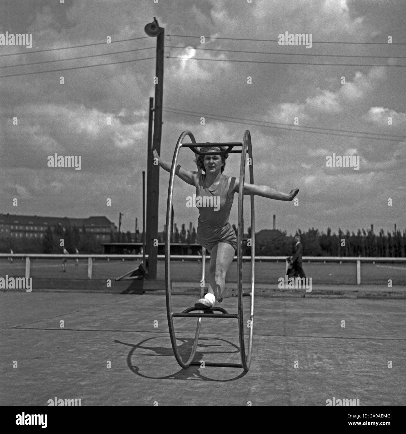 Una giovane donna che esercitano con il suo gymwheel su un terreno sportivo, Germania 1930s. Foto Stock