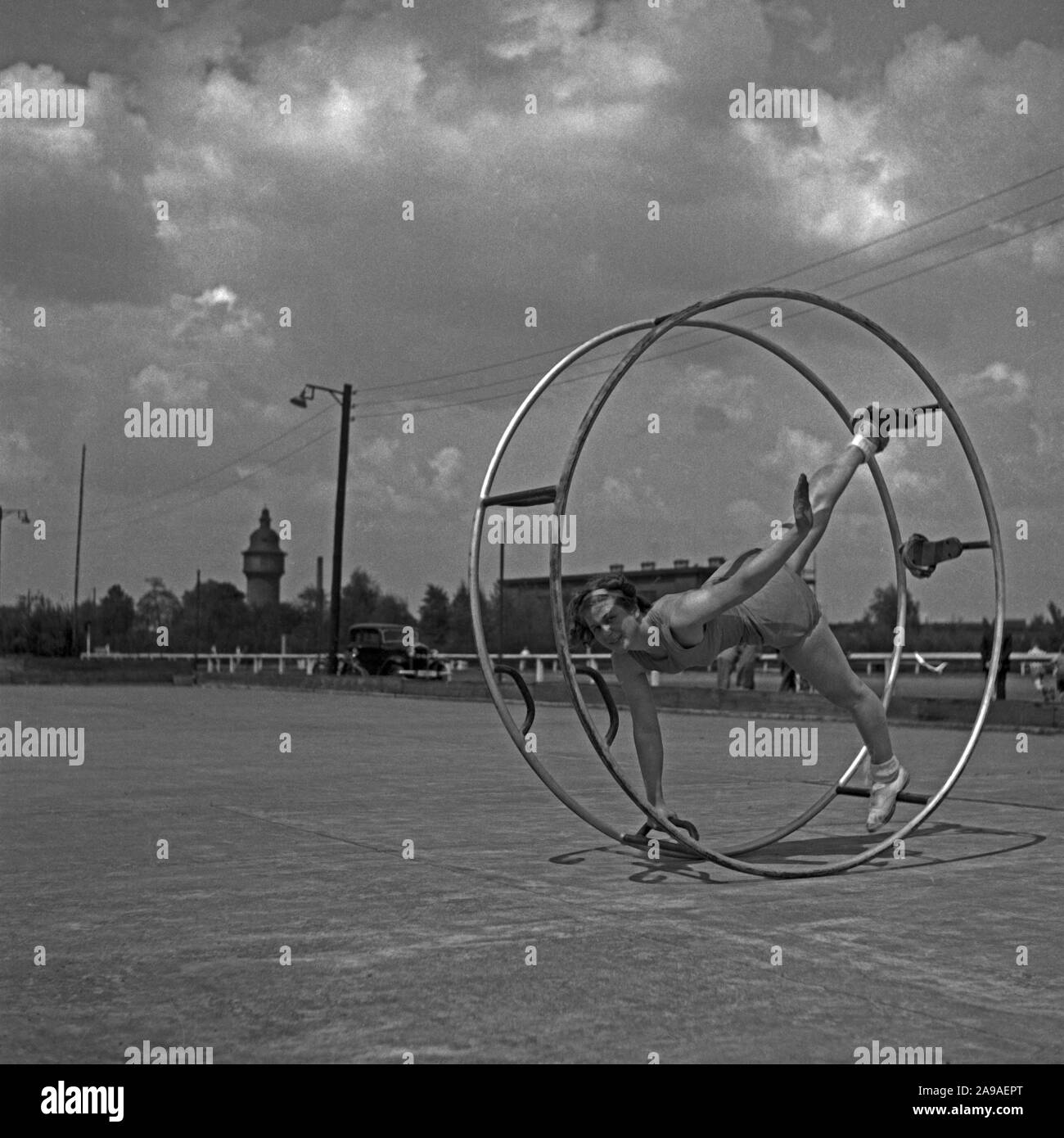 Una giovane donna che esercitano con il suo gymwheel su un terreno sportivo, Germania 1930s. Foto Stock