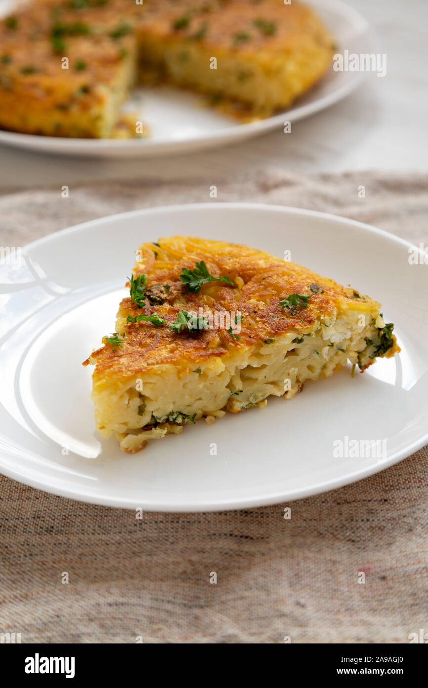 Un pezzo di frittata di spaghetti su una piastra bianca, vista laterale. Close-up. Foto Stock