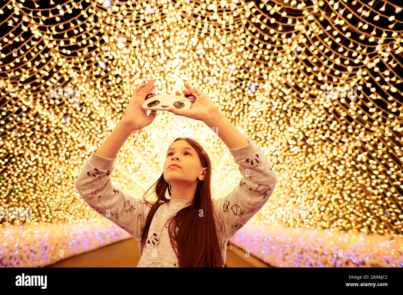 Ragazza giovane di scattare le foto con il suo smartphone al tunnel di luci in Nabana No Sato, Giappone. Foto Stock