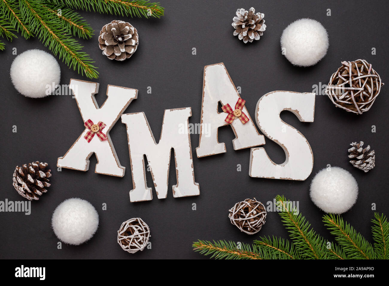 XMAS lettere circondato da albero di Natale rami, sfere e coni decorazioni. Vista superiore della composizione, laici piana. Foto Stock