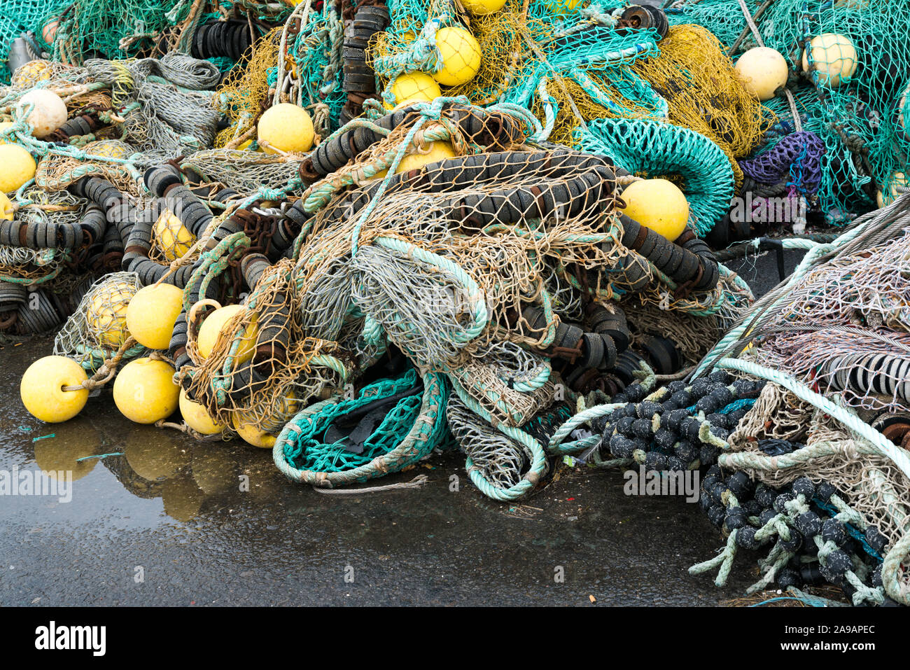 Un gran mucchio di diverse reti da pesca utilizzati per la pesca di mare e la pesca a strascico la posa sul dock Foto Stock