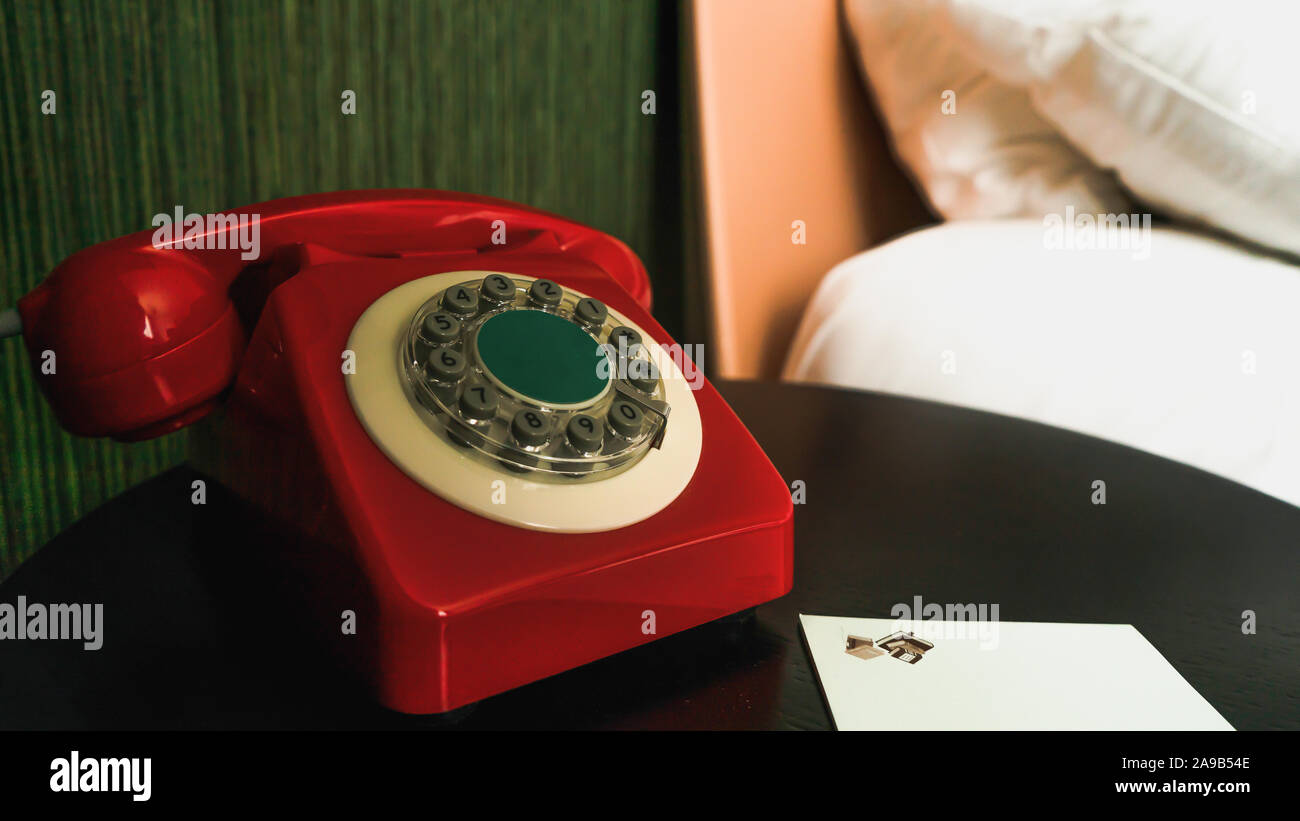 Close-up sul rosso, vintage Ricerca telefono con pulsanti sul comodino con il blocco note e matita Foto Stock