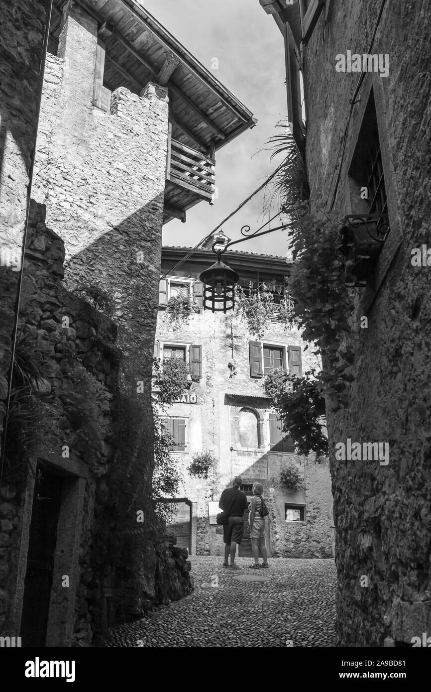 Via Fratelli Bandiera, uno stretto vicolo che conduce alla piazza centrale, in colle medievale borgo di Canale di Tenno, Trentino-Alto Adige, Italia. b/w Foto Stock