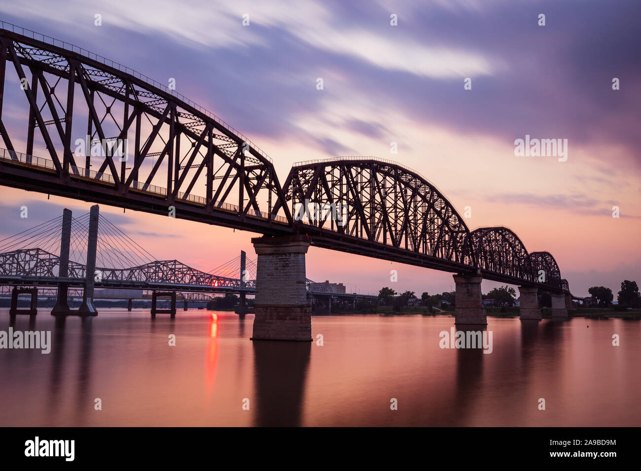 Una lunga esposizione delle quattro grandi ponte di Louisville, KY con un tramonto di nuvole che si muovono e acqua liscia come seta. Foto Stock