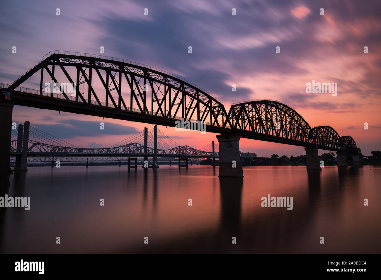 Una lunga esposizione delle quattro grandi ponte di Louisville, KY con un tramonto di nuvole che si muovono e acqua liscia come seta. Foto Stock