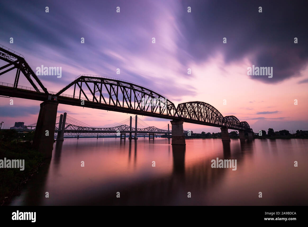 Una lunga esposizione delle quattro grandi ponte di Louisville, KY con un tramonto di nuvole che si muovono e acqua liscia come seta. Foto Stock