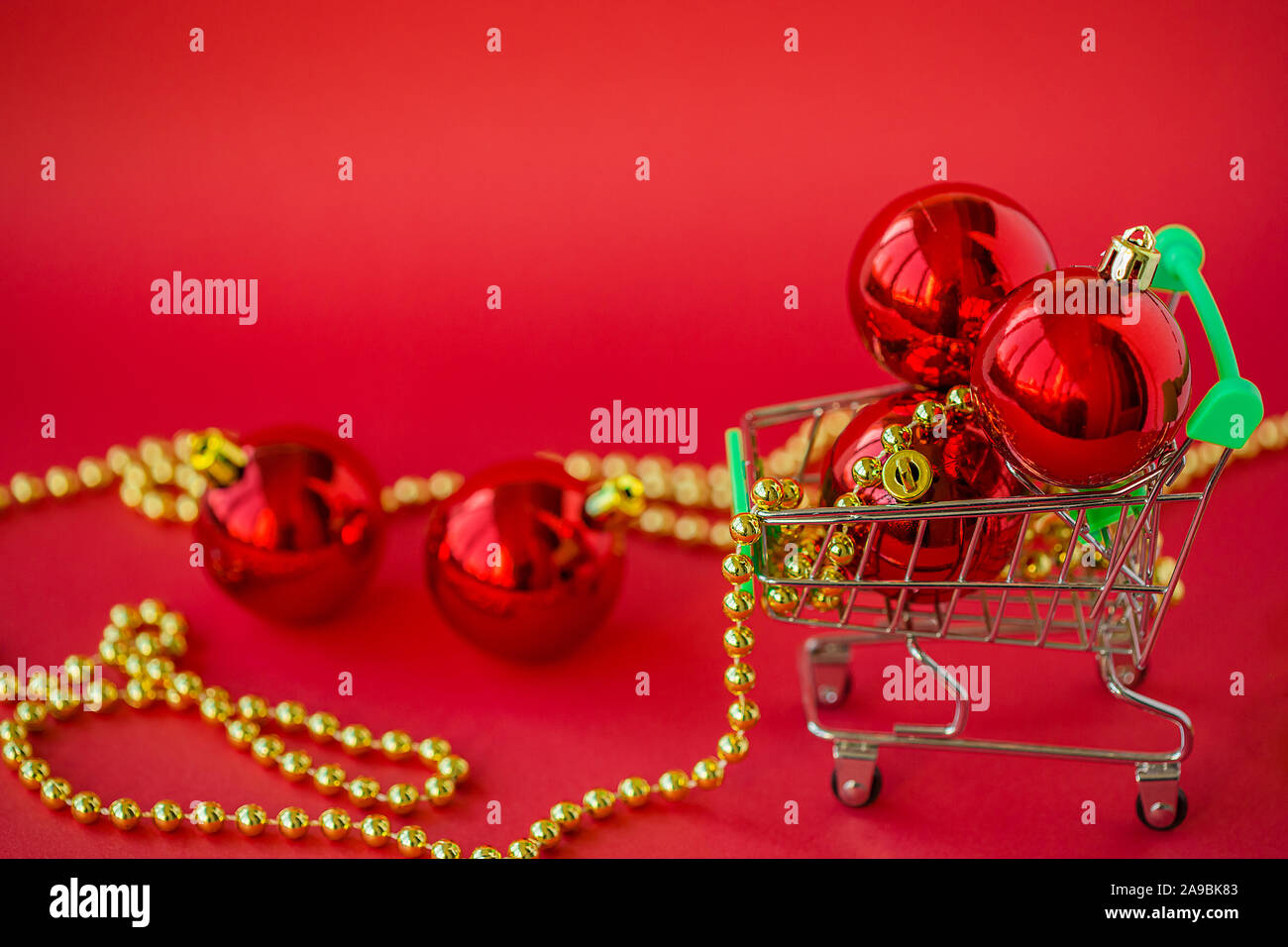 Regalo palle di Natale in una miniatura del carrello e decorazioni su uno sfondo di colore rosso. Natale e Anno Nuovo Vendita, Natale Online Store. Foto Stock