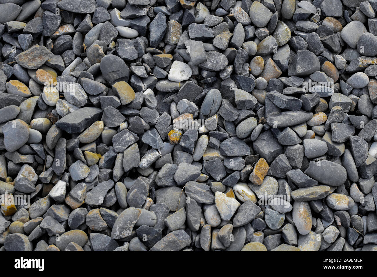Ghiaia di piccole e medie dimensioni e di colore grigio scuro pietre di colore giallo - sfondo Foto Stock
