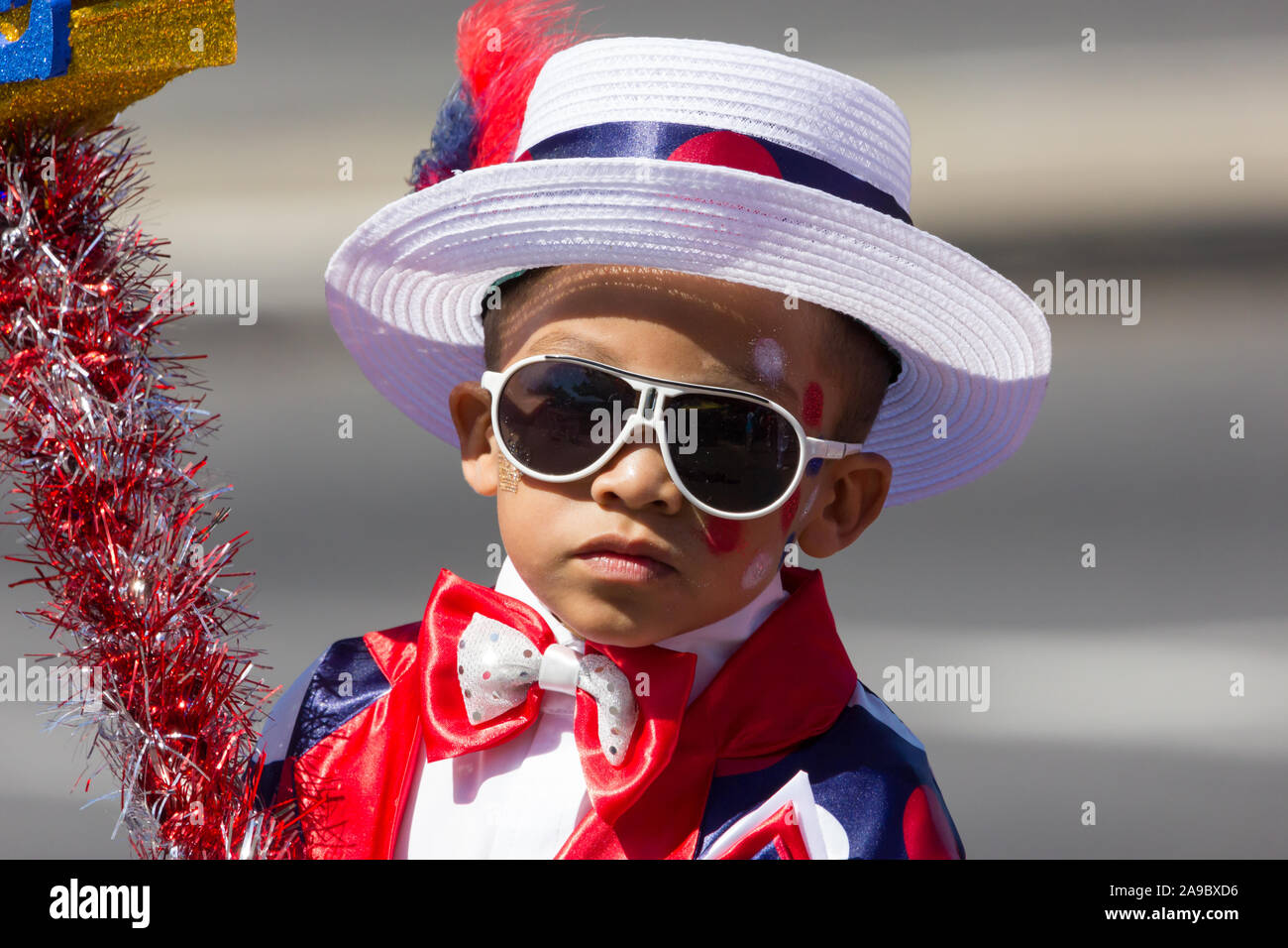 Ritratto e il primo piano del volto di una giovane razza mista bambino, un ragazzo di circa 5 anni, indossando occhiali da sole bianco vestito in abiti fantasiosi costumi Foto Stock