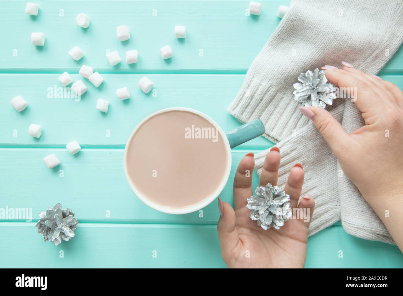 Una tazza di bevanda invernale con dolci natalizi e coni di argento, turchese sfondo tabella, vista dall'alto. Foto Stock