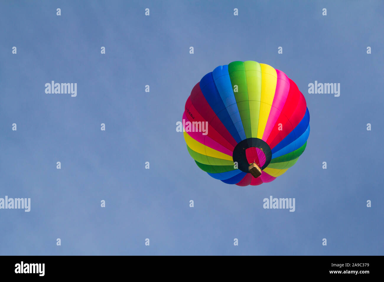 Una mongolfiera in/contro un cielo blu chiaro con strisce di colori multipli. Adatto per il concetto e lo spazio per testo/copia. Foto Stock