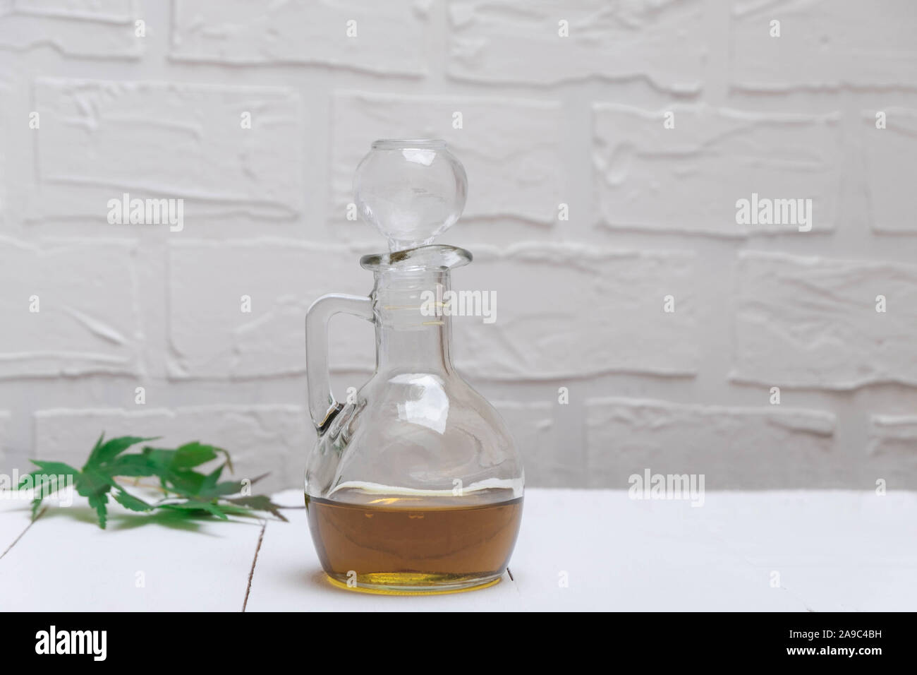La cannabis naturale CBD di olio in un vasetto di vetro sul tavolo bianco Foto Stock