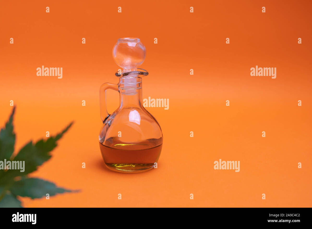 Materie olio di cannabis in una bottiglia di vetro su sfondo arancione Foto Stock