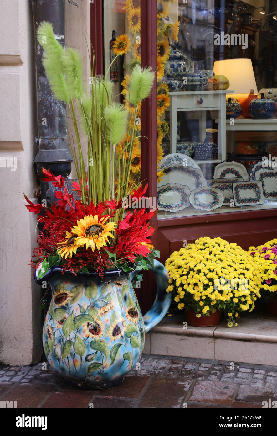 Cracovia. Cracovia. La Polonia. Boeslawiec negozio di ceramica decorazione nella parte anteriore del negozio. Vaso con artificiali e fiori naturali. Foto Stock