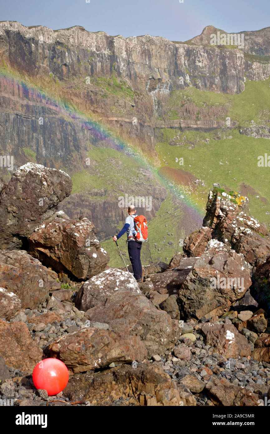 Walker guardando l'arcobaleno frastagliate scogliere sull'Isle of Mull. Queste scogliere remoto chiamato Binnein Gorrie sono conosciuto localmente come 'Gorrie's Leap' Foto Stock