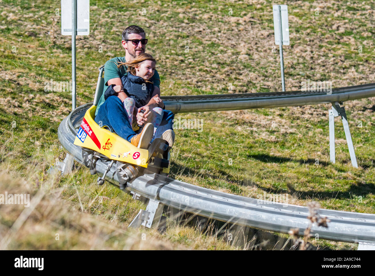 Padre con bambino sulla pista di slittino estivo / summer rodelbahn via / fun bob Foto Stock