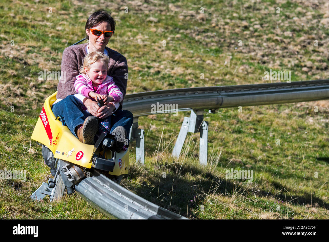 Madre con bambino sulla pista di slittino estivo / summer rodelbahn via / fun bob Foto Stock
