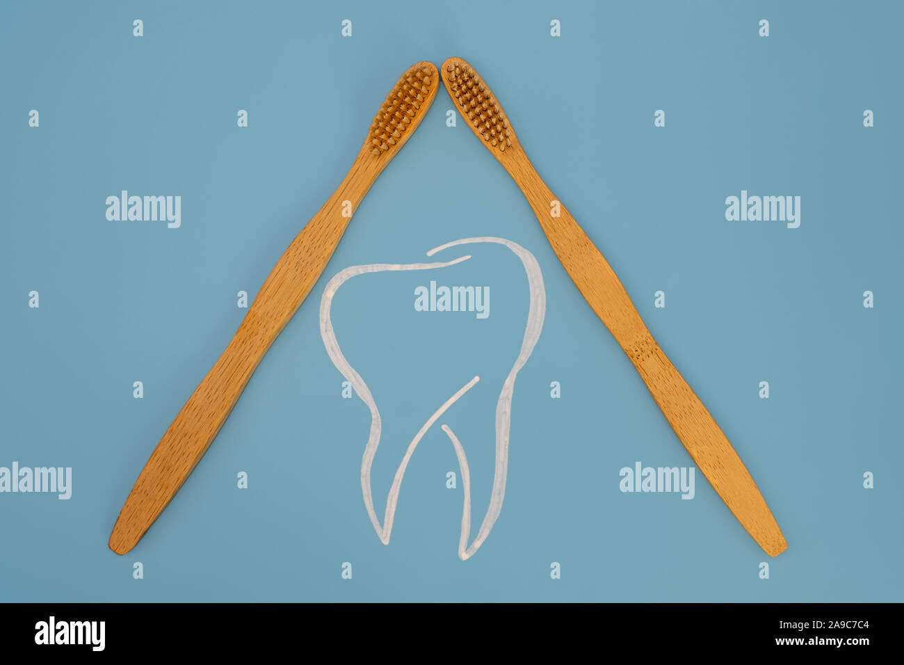Due spazzolini da denti simbolicamente proteggere un dente dipinta su uno sfondo blu Foto Stock