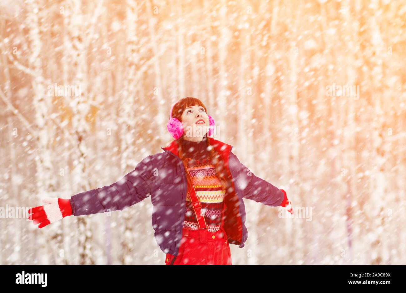 Ritratto di donna redhead sulla passeggiata invernale nel parco. caduta di neve Foto Stock