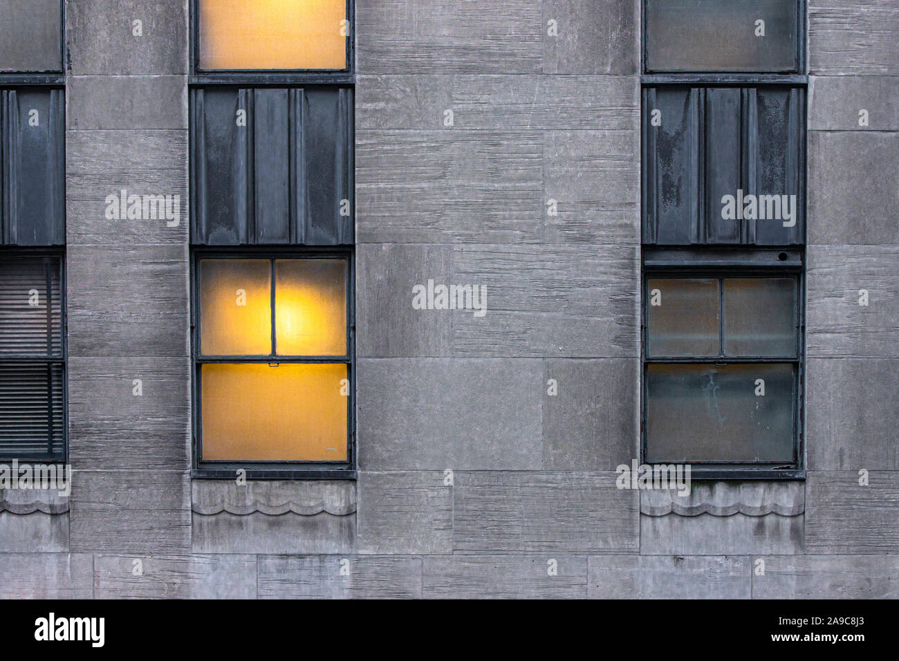 Windows simmetrici, uno illuminato e uno scuro su edifici urbani Foto Stock