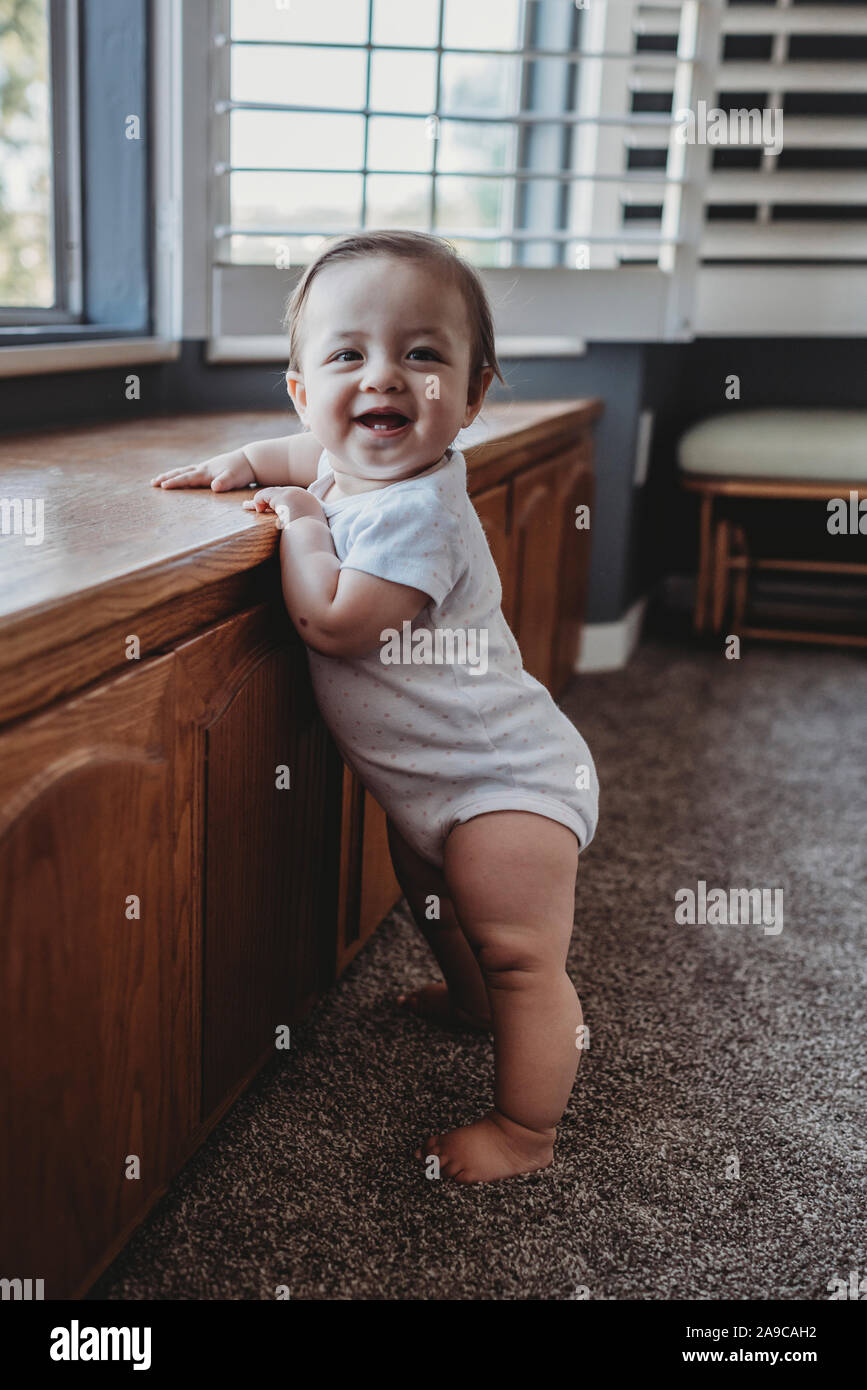 Sorridenti baby con due denti in piedi da una finestra Foto Stock