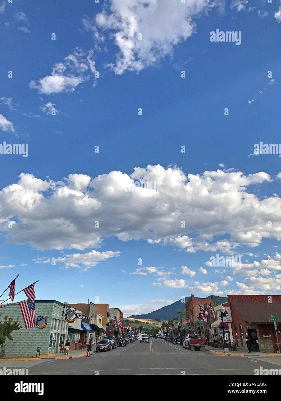 Città di montagna con cielo blu e nuvole, montagne, bandierine americane Foto Stock