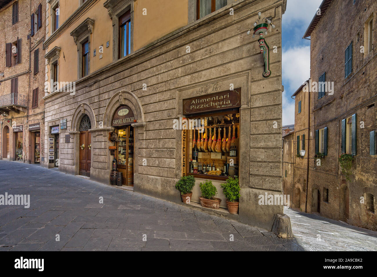 Negozio locale per la vendita di prosciutto, vino, formaggi e altri prodotti locali su la medievale strada stretta a Siena, Toscana, Italia Foto Stock