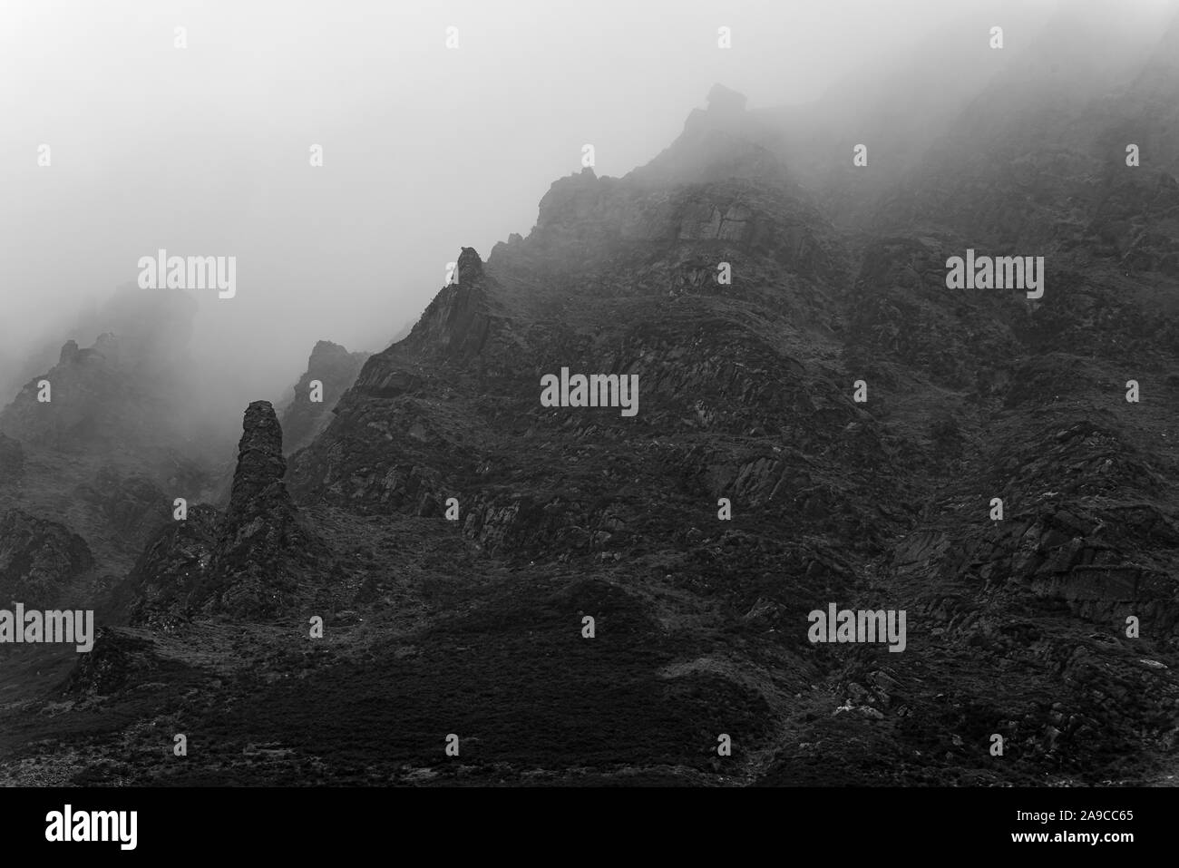 oscura montagna rocciosa, oscurata dalla nebbia, con più strapiombi o guglie. monocromatico Foto Stock