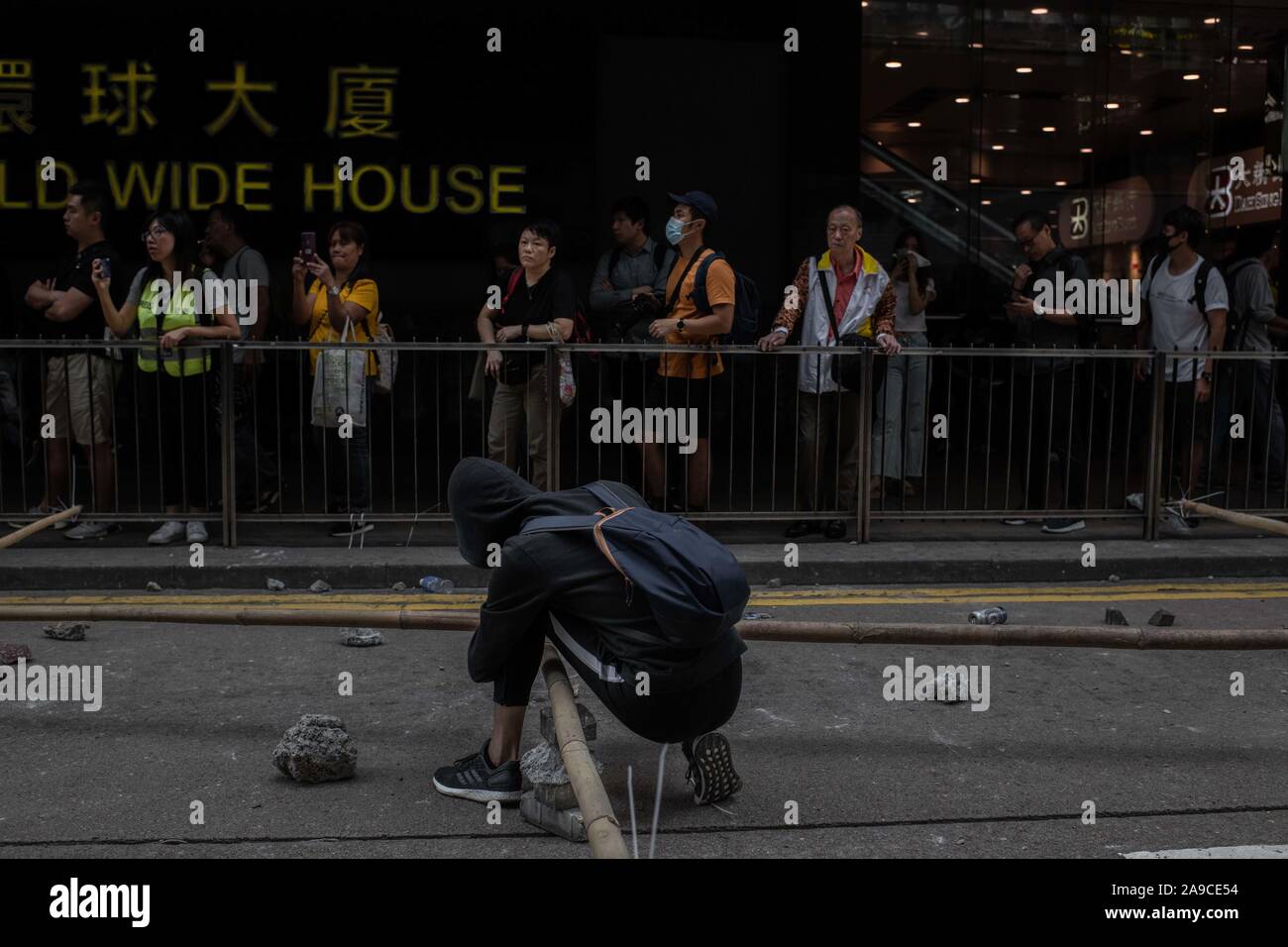 Un manifestante stringe un bastone di bambù per bloccare il Des Voeux Road durante la dimostrazione.manifestanti hanno chiesto per un giorno di sciopero il terzo giorno consecutivo. Governo anti-manifestanti hanno bloccato le strade e gli accessi della metropolitana nella zona centrale di Hong Kong. Un relativamente calma giorno dopo la violenza era tornato in risposta ad azioni di polizia lunedì quando almeno due manifestanti sono stati girati e molti altri feriti. Foto Stock