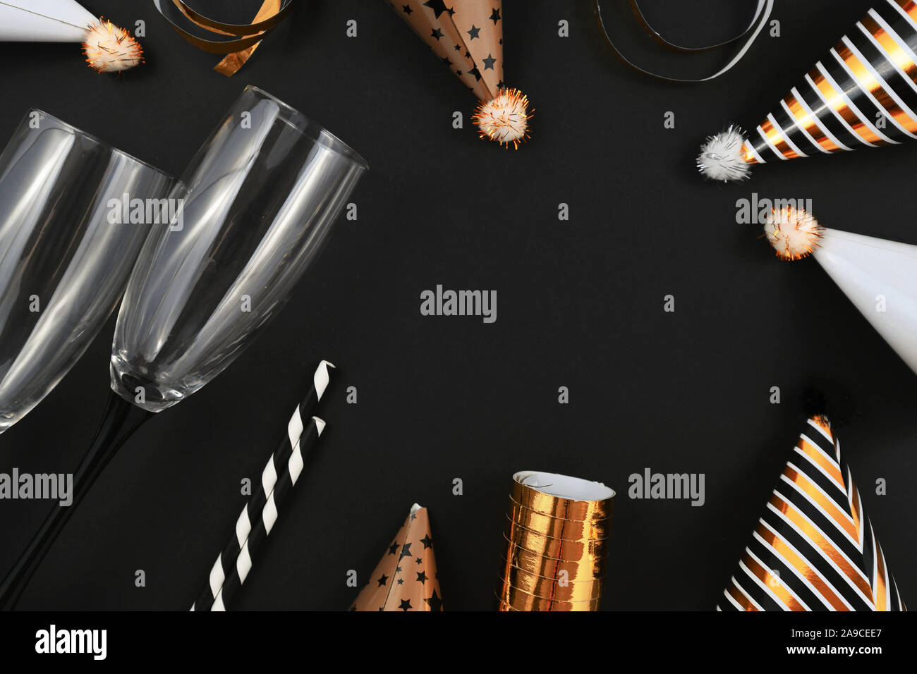 Anno nuovo Silvester celebrazione laici piatta con champagne bicchieri, oro e bianco cappelli di partito, scoppi e striato rinking cannucce su nero bac Foto Stock