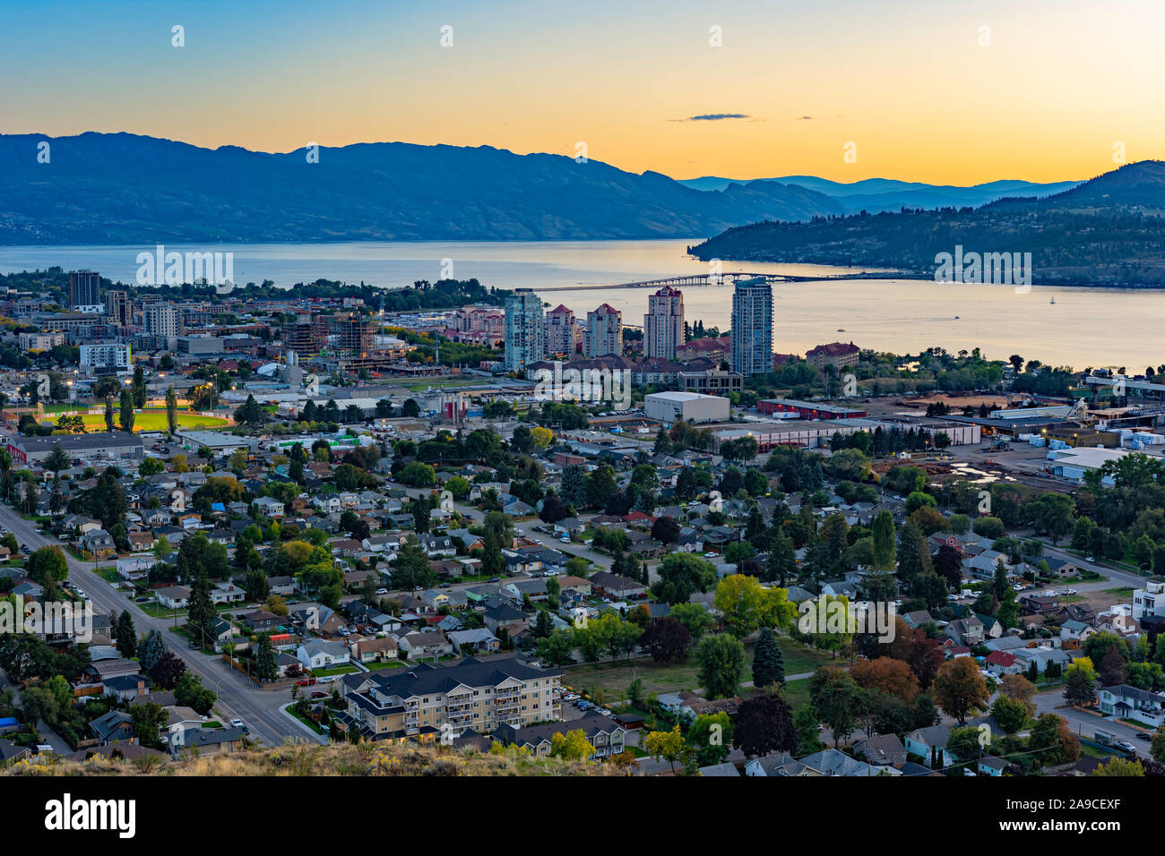 Una vista di Kelowna British Columbia skyline e Lago Okanagan dalla montagna di Knox dopo il tramonto Foto Stock