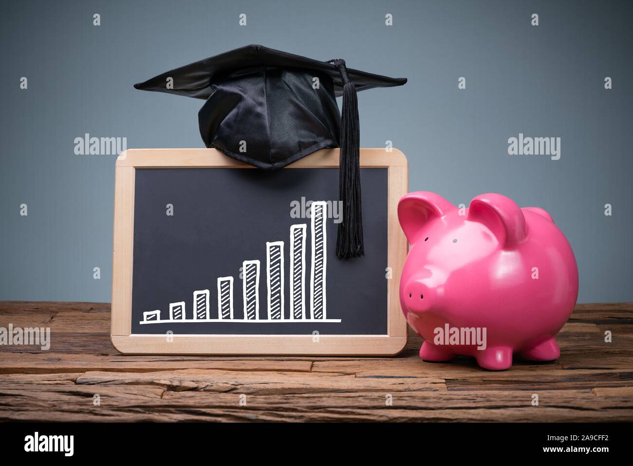 Close-up di Rosa Piggybank davanti di Blackboard Mostra grafico Foto Stock