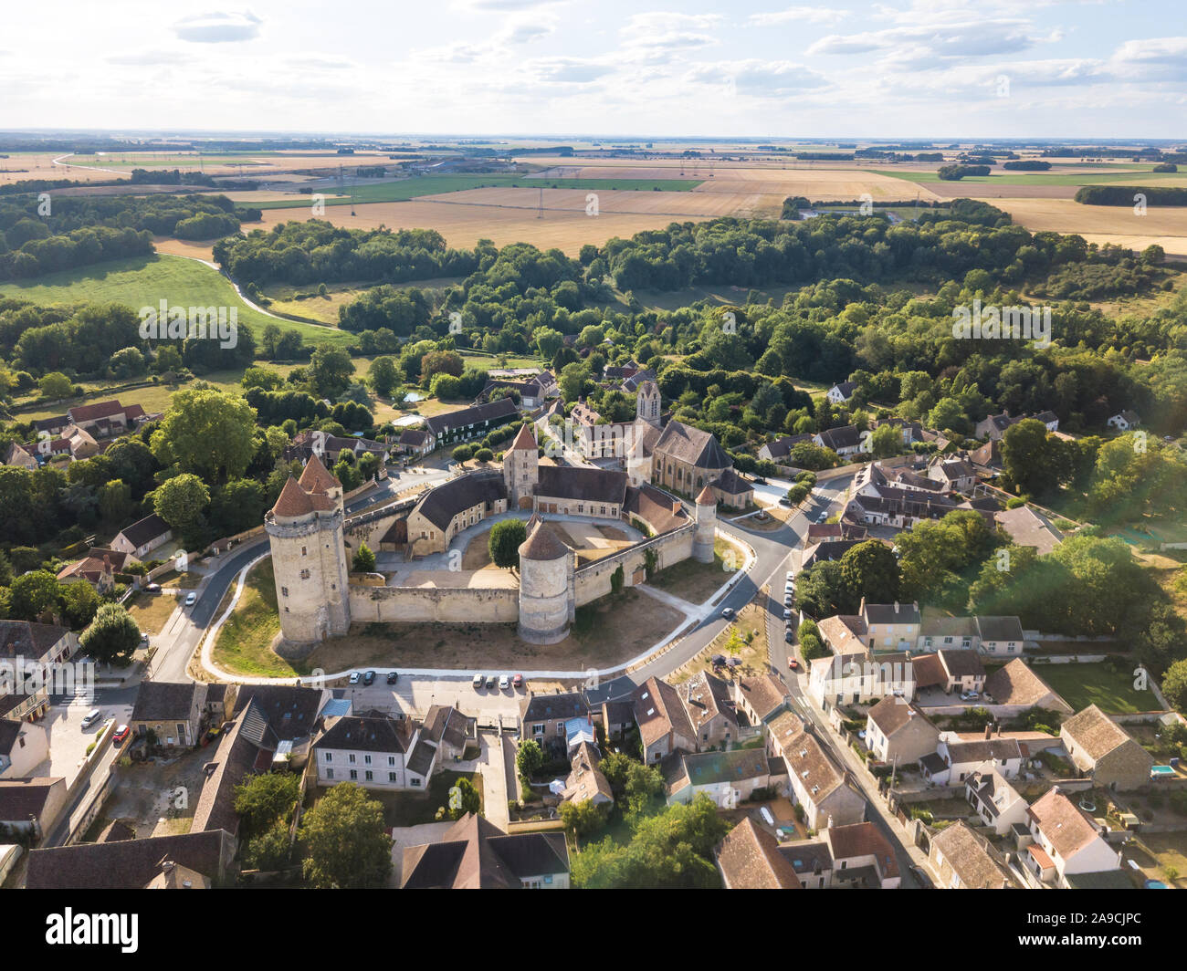 Castello medievale con le mura fortificate e torri e mastio nel villaggio rurale in Francia, vista aerea da fuco di rinnovata fortezza dal medio evo, scen Foto Stock