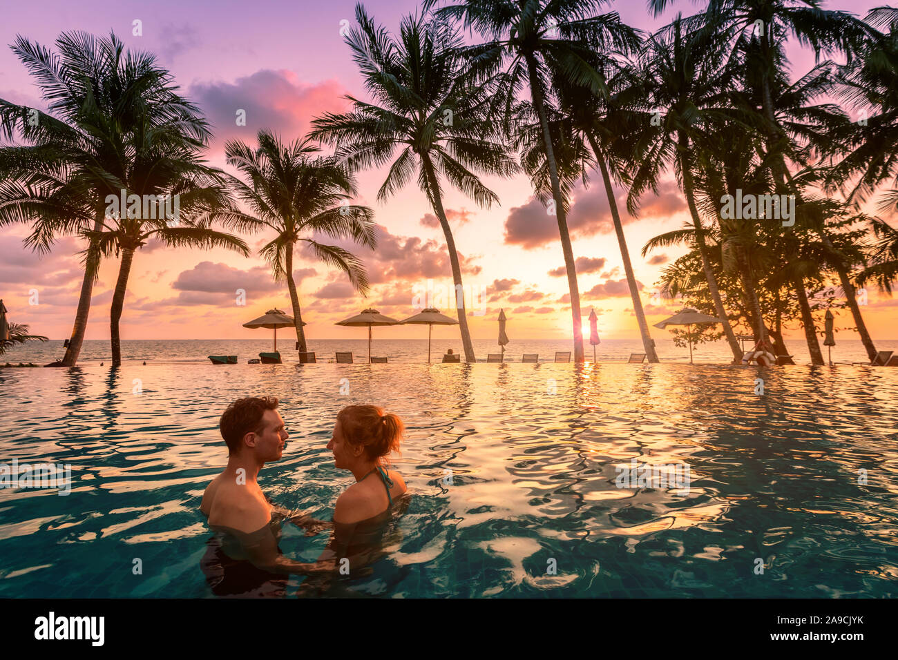 Coppia al beach vacation resort di vacanza rilassante in piscina con scenic paesaggio tropicale al tramonto, estate romantica luna di miele isola destinat Foto Stock