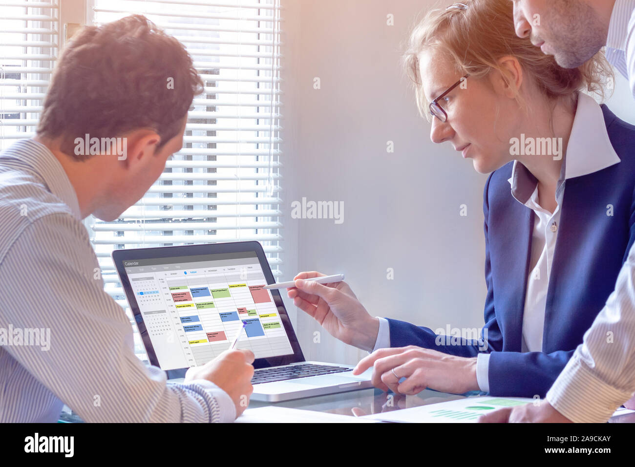 Team pianificazione di un incontro con il calendario sul computer, cercare slot di tempo tra eventi, attività e appuntamenti, busy business persone usando time managemen Foto Stock